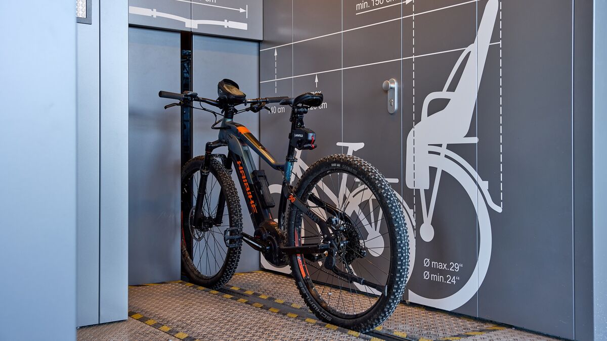 Bicicleta sobre un raíl delante de un sistema automático de aparcamiento para bicicletas