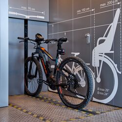 Bicicleta sobre un raíl delante de un sistema automático de aparcamiento para bicicletas