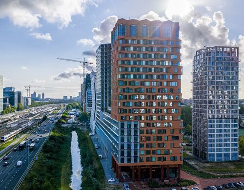 Exterior view of The Pulse project in Amsterdam featuring modern high-rise buildings and urban transport infrastructure.