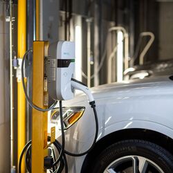 Un vehículo está estacionado en la plataforma de un sistema de aparcamiento y se está cargando mediante la instalación integrada de carga para vehículos eléctricos.