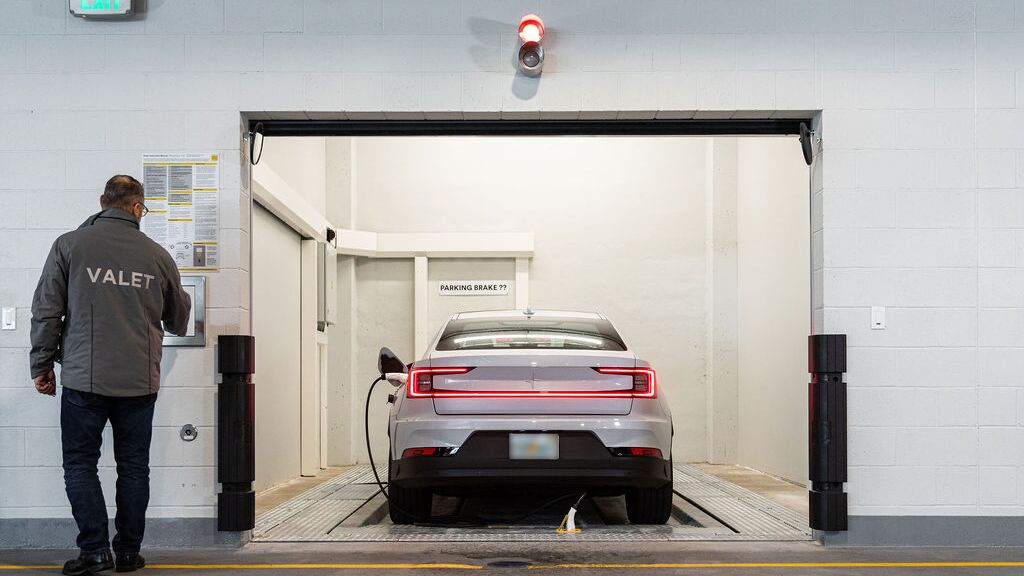 La imagen muestra la zona de entrega de un sistema de aparcamiento automatizado, donde el conductor inicia el proceso de estacionamiento para que el vehículo sea transportado y aparcado automáticamente dentro del sistema.