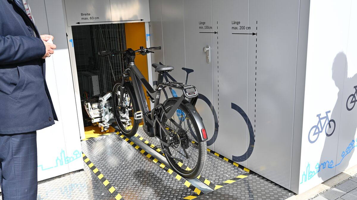 Bicicleta sobre un riel delante de un sistema automático de aparcamiento de bicicletas