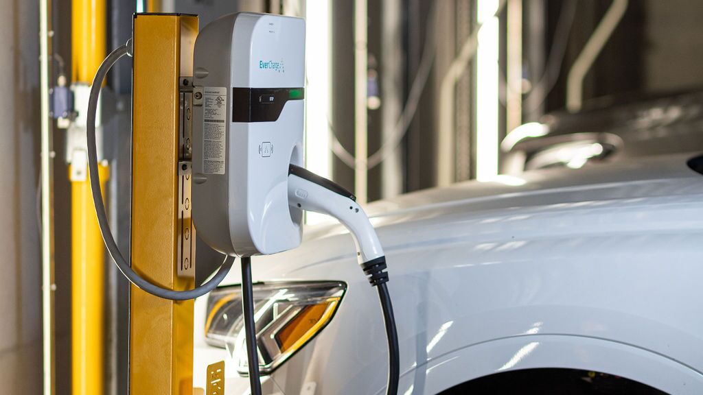 Un vehículo está estacionado en la plataforma de un sistema de aparcamiento y se está cargando mediante la instalación integrada de carga para vehículos eléctricos.