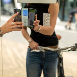 Una mujer con una bicicleta escanea un código QR en el sistema de aparcamiento para bicicletas