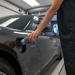 Una mujer conecta un conector de recarga eléctrica al coche
