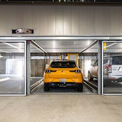 La imagen muestra un moderno garaje subterráneo con varias plazas acristaladas de un sistema de estacionamiento.
