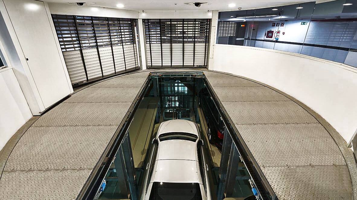 El coche se encuentra en una cabina de entrada sobre una plataforma de aparcamiento y desciende