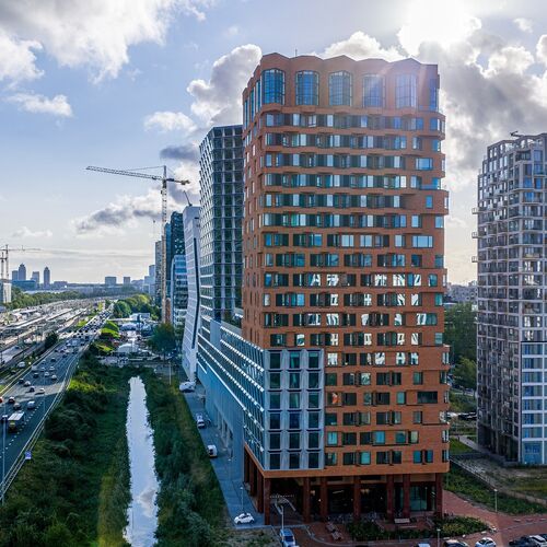 Exterior view of The Pulse project in Amsterdam featuring modern high-rise buildings and urban transport infrastructure.