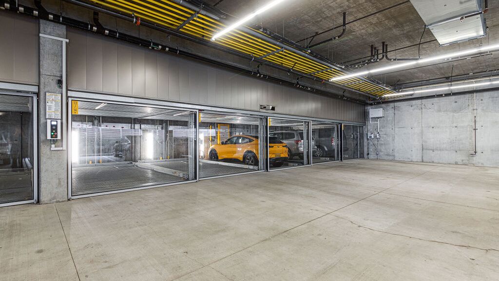 La imagen muestra un moderno garaje subterráneo con varias plazas acristaladas de un sistema de estacionamiento.
